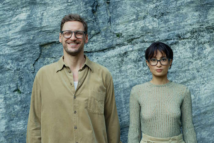 Ein Mann und eine Frau mit Brille posieren vor Felswand – moderne Darstellung sozialer Nachhaltigkeit.