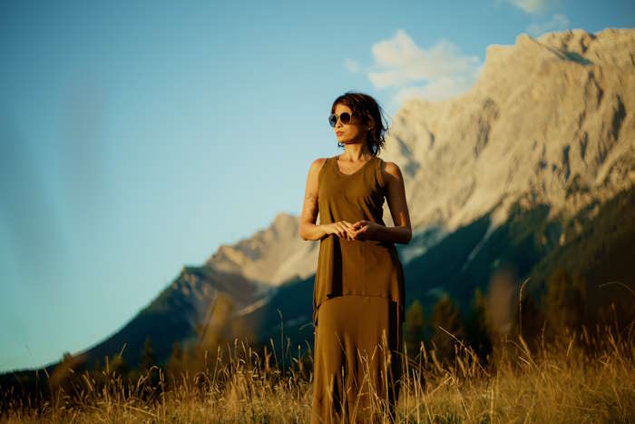 Modebewusste Frau in olivgrünem Outfit mit Sonnenbrille mit Tönung in Berglandschaft - Beitrag Tönung bei Sonnenbrillen