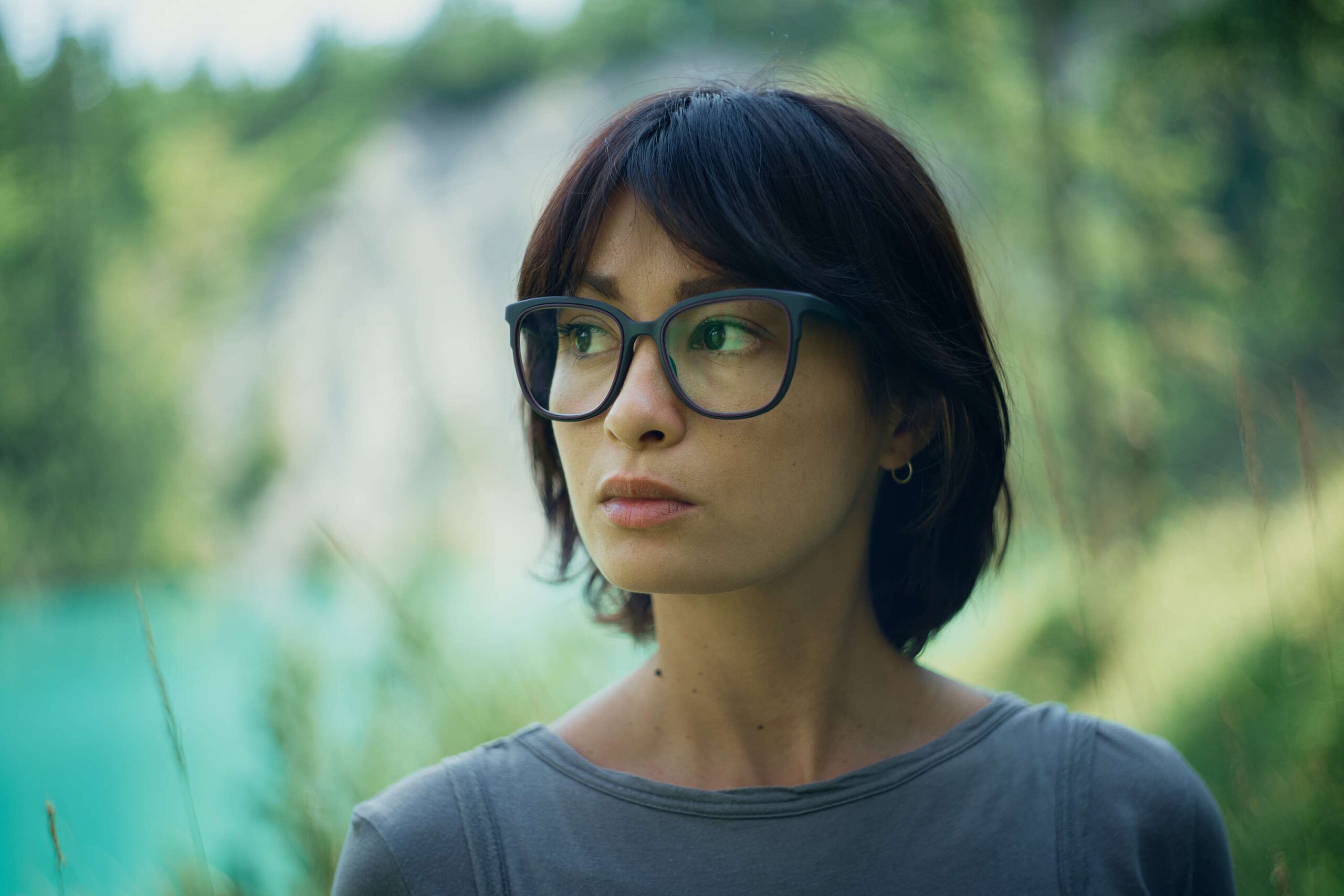 Nachdenkliche Frau mit Brille im Grünen als Inspiration für "Augen schminken"