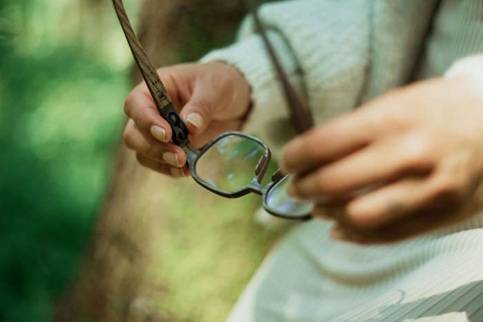 Detailansicht einer Hand, die eine Holzbrille von Rolf hält