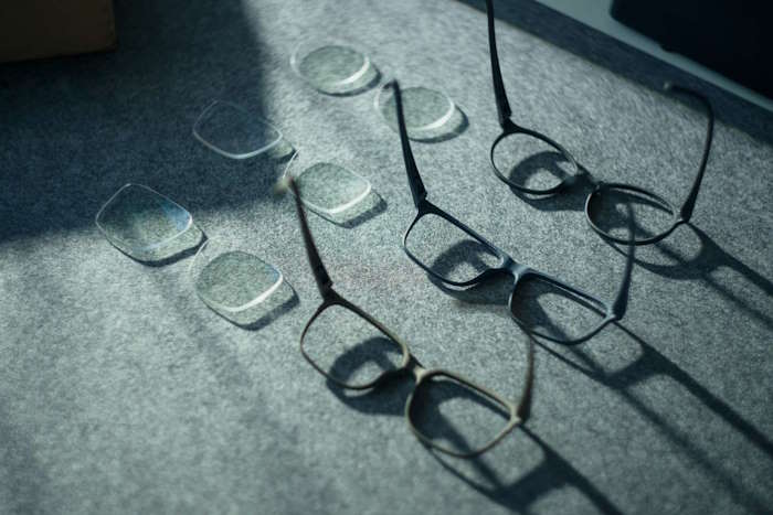 Mehrere Hornbrillenrahmen und Brillengläser auf einem Tisch