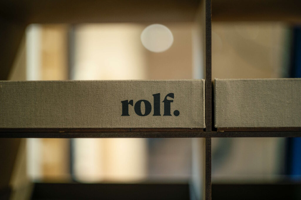 Ein Regal mit Leinenstruktur und dem Schriftzug "rolf." – passend für hochwertige Männerbrillen für den Sommer.