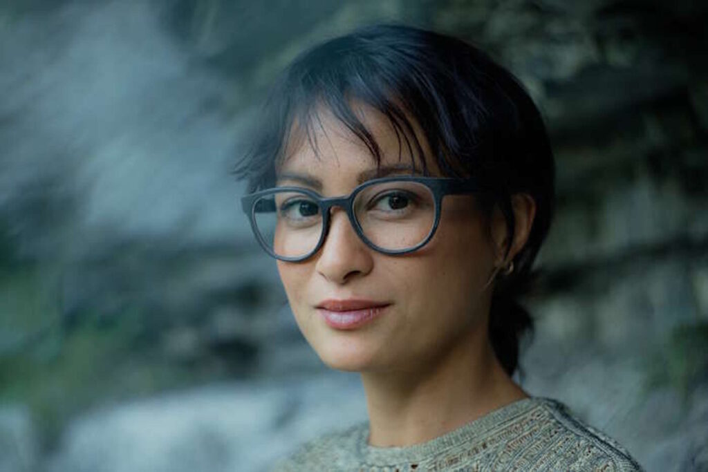 Nahaufnahme einer lächelnden Frau mit stylischer Damenbrille für den Sommer vor verschwommenem Hintergrund.