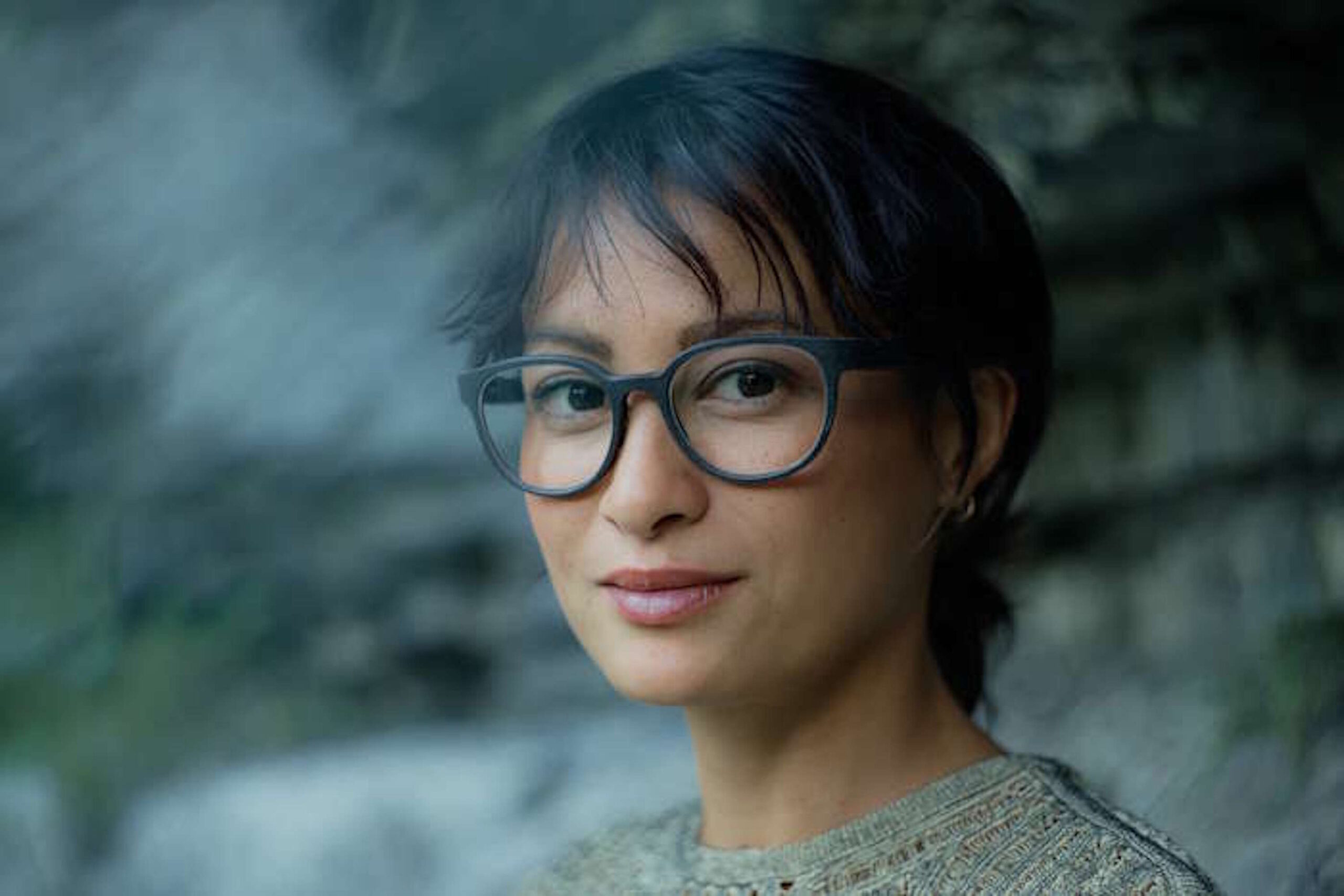 Nahaufnahme einer lächelnden Frau mit stylischer Damenbrille für den Sommer vor verschwommenem Hintergrund.