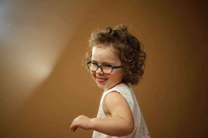 Lächelndes Kind mit blauer Brille, ideal für Kinderbrillen für die Ferien