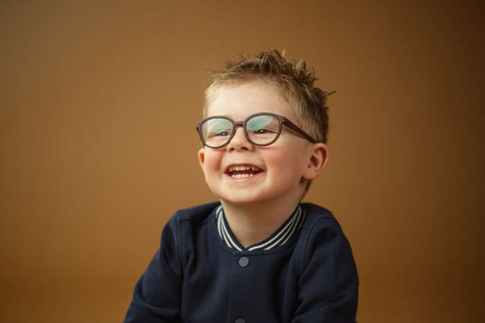 Lachender Junge mit moderner Brille, ideal für Kinderbrillen für die Ferien