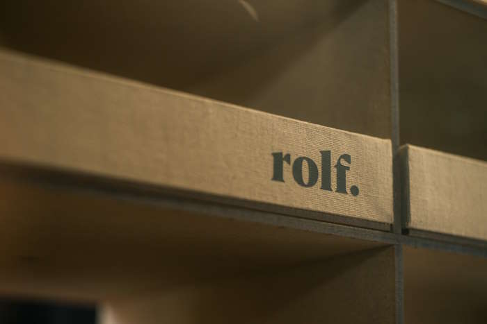 Nahaufnahme eines Regals mit dem Schriftzug „rolf.“ auf einem Holzbrett. Perfekt für Brillen für Abenteurer.