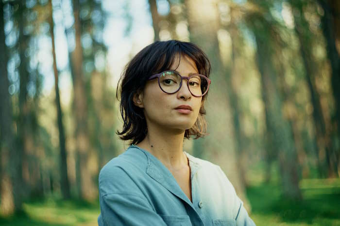 Frau mit modernem Brillendesign im Wald, ideal für Damenbrillen für den Sommer