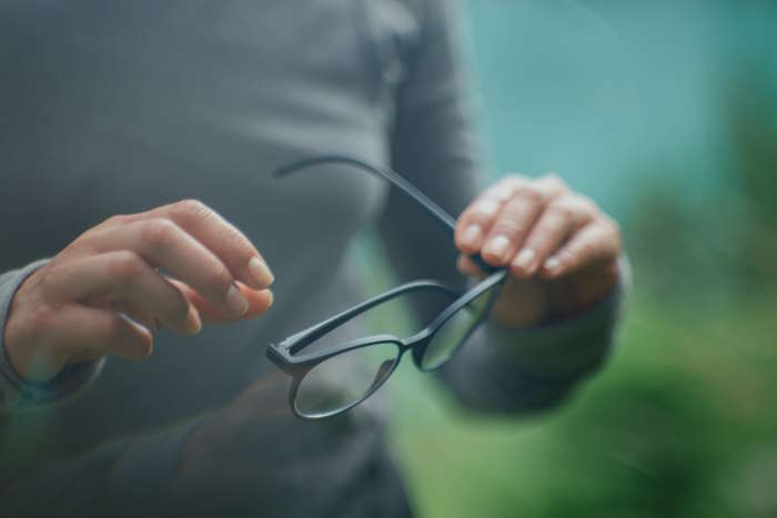 Person hält eine schwarze Brille in den Händen, überlegt welche Brillenfarbe zu welchem Typ passt.