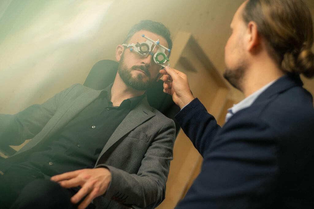 Ein Mann mit einem optischen Messgerät während einer Augenuntersuchung, betreut von einem Fachmann – ideal für das Thema "Augenfarbe im Alter".