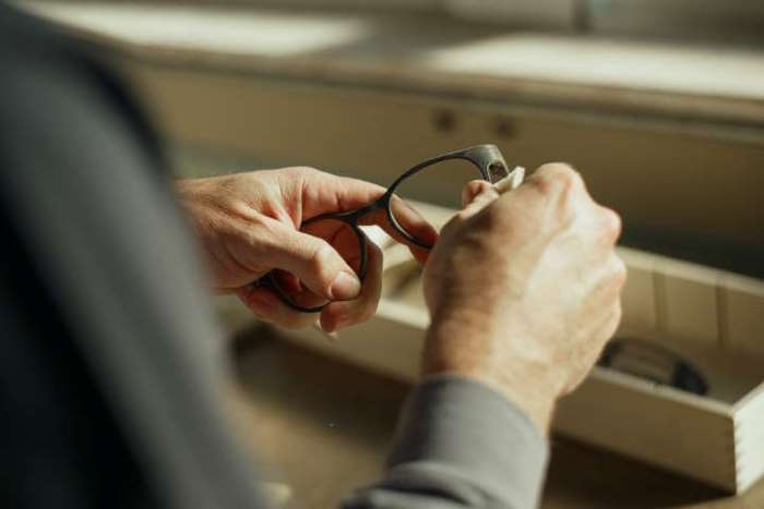 Nahaufnahme von Händen, die eine Brille reinigen – Fakten übers Sehen.