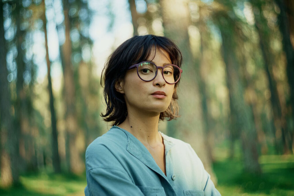 Eine Frau mit Brille in einem lichtdurchfluteten Wald – Fakten übers Sehen.