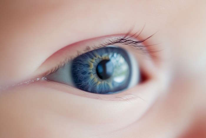 Detailaufnahme eines Babyauges mit blauer Iris, umgeben von weicher Haut.