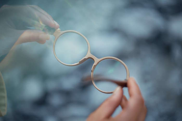 Detailaufnahme einer beigen, runden Holzbrille in der Hand gehalten, passend für einen hilfreichen Brillen Ratgeber.