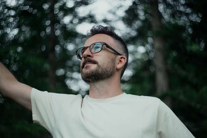 Mann mit Brille im Wald blickt nach oben