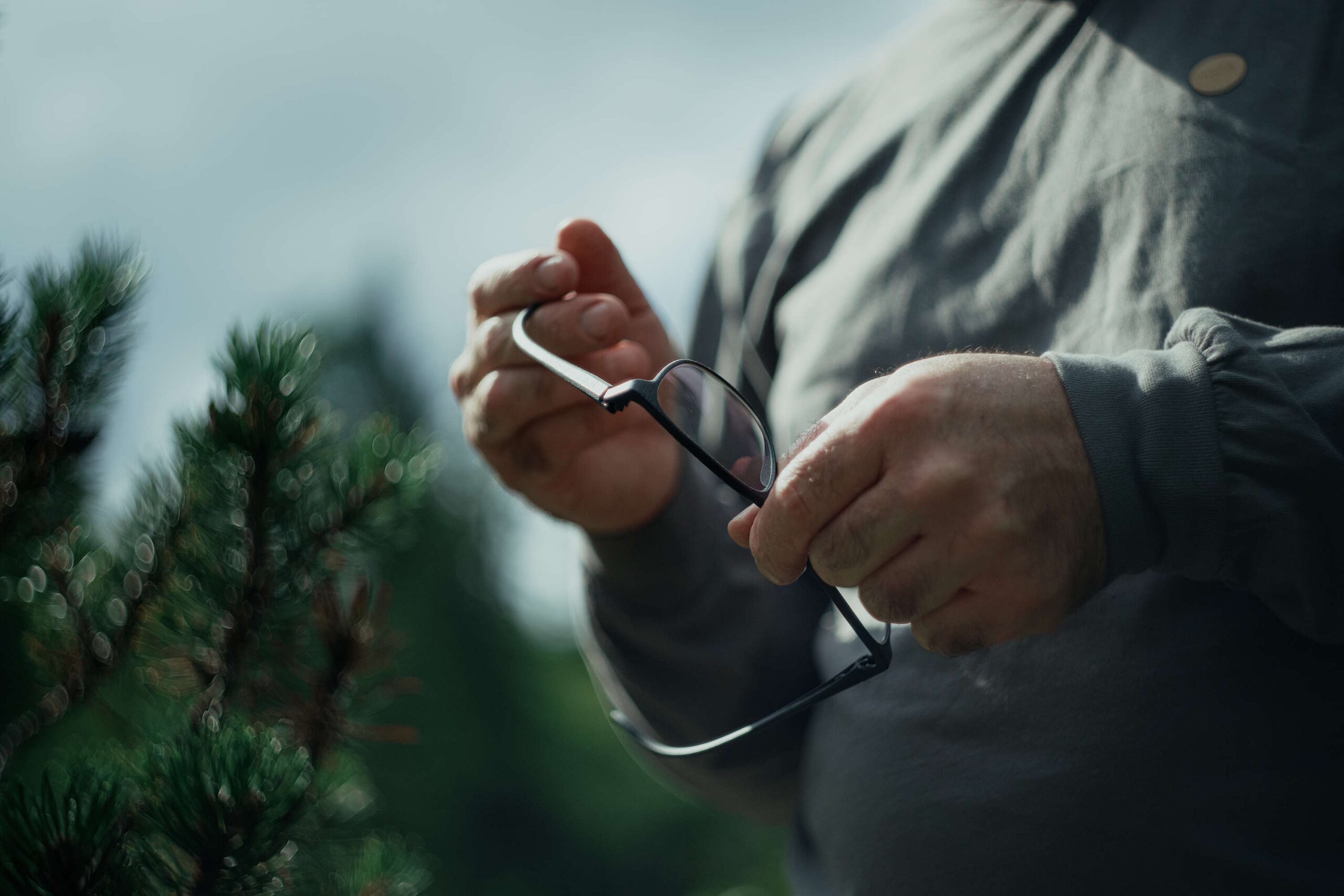 Mann hält eine Brille in der Natur – Made in Tirol