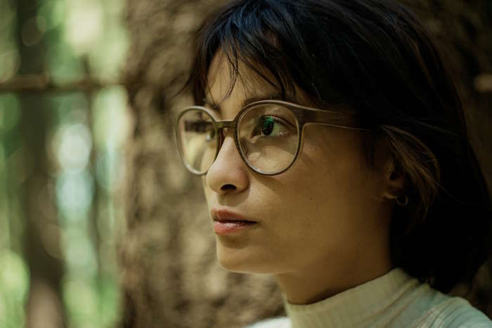 Porträt einer Frau mit großer Brille im Wald – Ausdruck für die Langlebigkeit von Brillen im Alltag.
