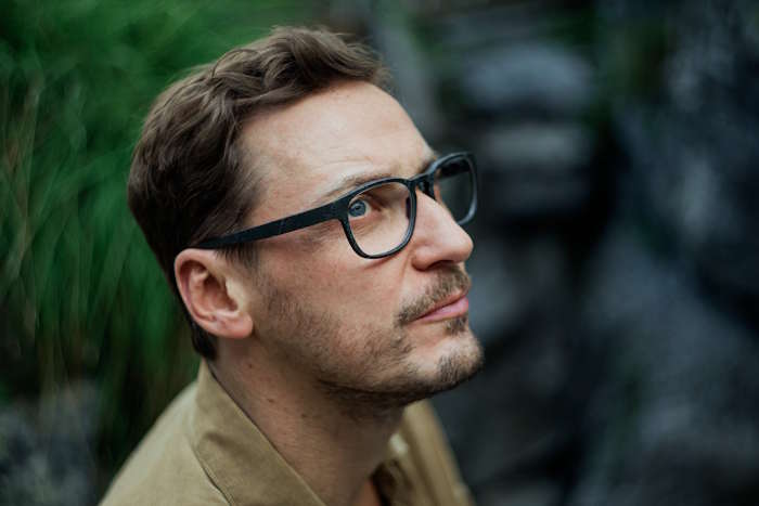 Mann mit Brille blickt nach oben im Freien – Wie entsteht eine Brille?