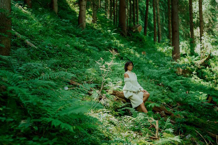 Frau mit Brille sitzt im Wald – welche Brille macht dich selbstbewusster?