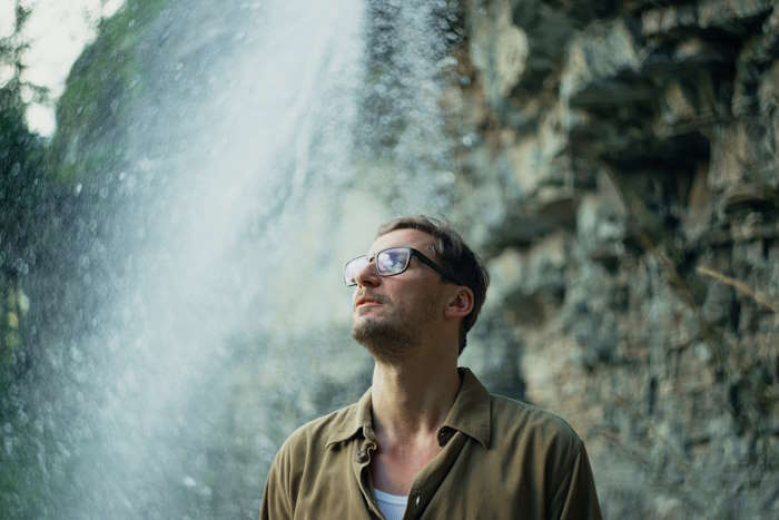 Mann mit Brille vor Wasserfall – welche Brille macht dich selbstbewusster?