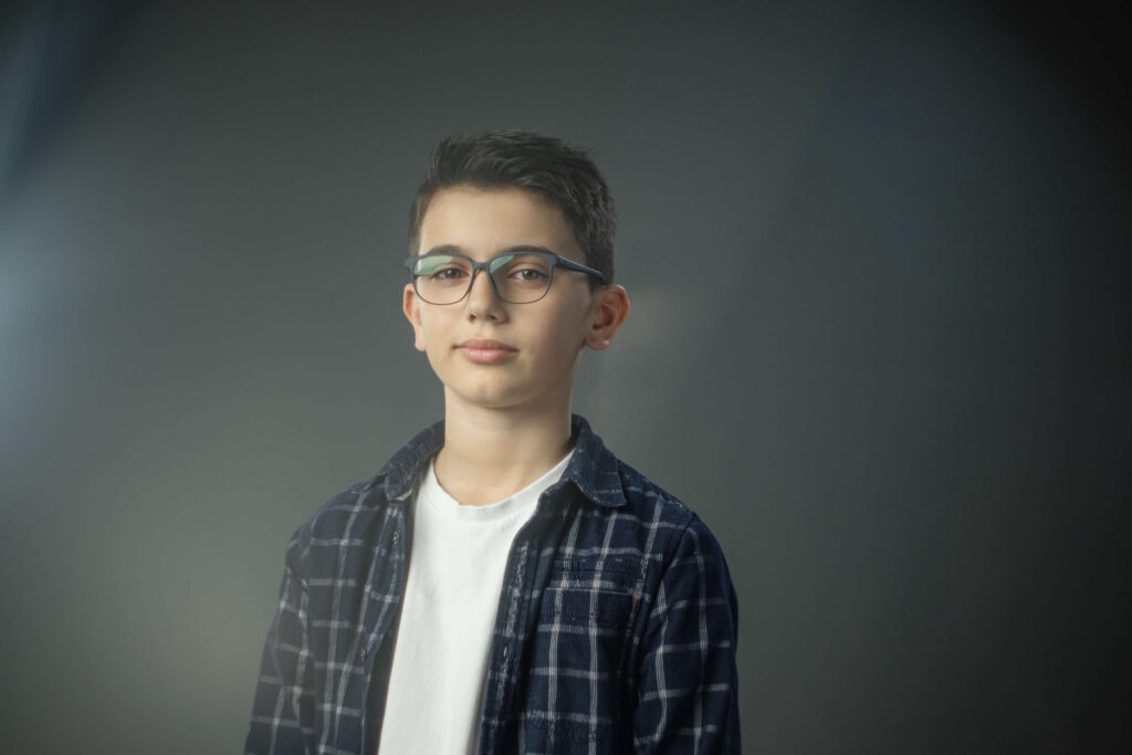 Junge mit Brille im Studio vor grauem Hintergrund – Brillen für Schulkinder