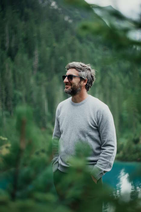 Mann mit grauen Haaren trägt Brillen für graue Haare und genießt die Aussicht im grünen Wald